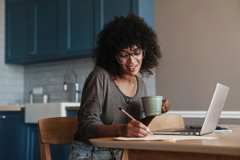 Woman researching tax credits on her laptop and taking notes to prepare for filing taxes.